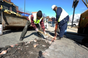 Boston Public Works Department employees Aroll Victor and Julio Echemendia clear rocks from a pothole in South Boston on March 12.