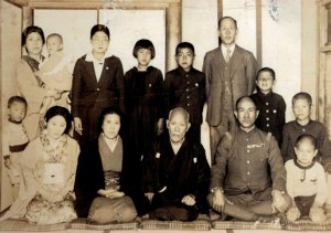 Together with my father who returned briefly from Manchuria in 1939. Front row from left: my mother Yukie, grandmother Tsuki, grandfather Kosaburo, father Chikara, younger brother Sadamu, and myself behind Sadamu, together with my uncle Eijiro Sata's family in back row.
