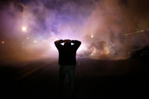 A protester stands with his hands on his head as a cloud of tear gas approaches after a grand jury returned no indictment in the shooting of Michael Brown in Ferguson, Missouri